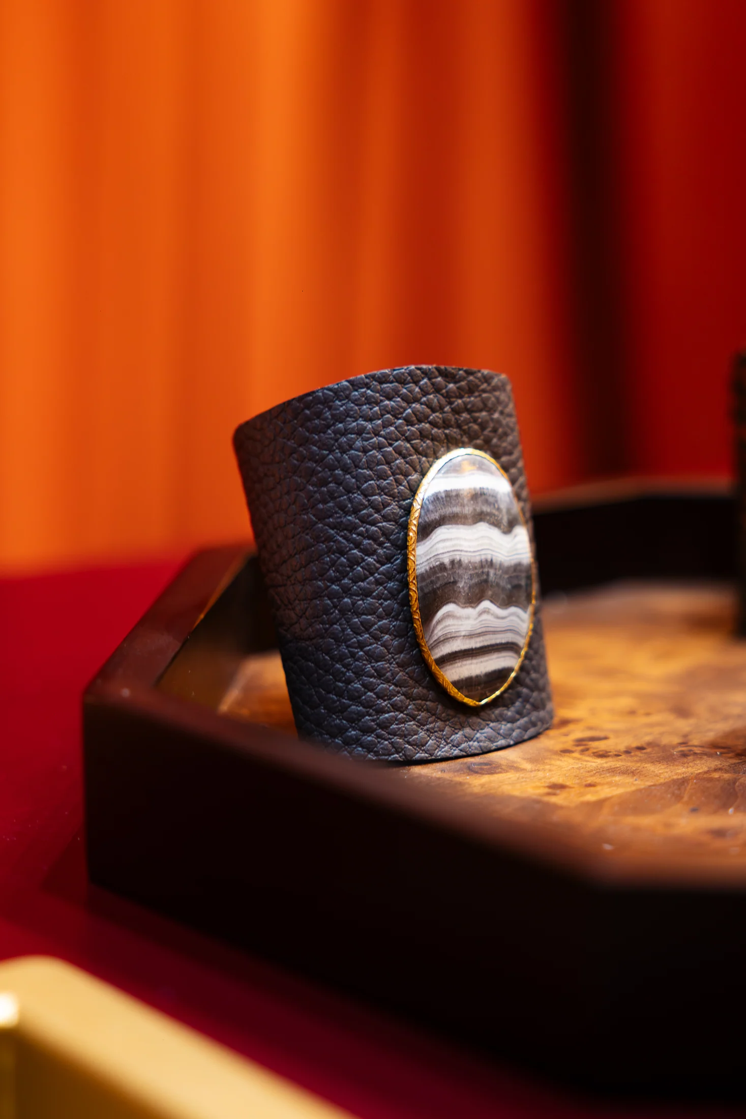 Balasoir agate cuff displayed against a warm orange backdrop, photographed by Ludovic Delot